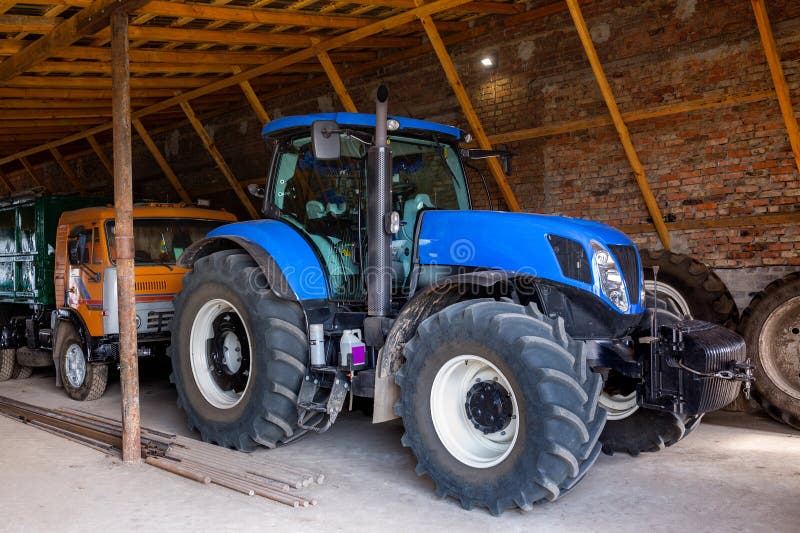 A New Modern Blue Tractor is Parked in a Farm Hangar Stock Photo