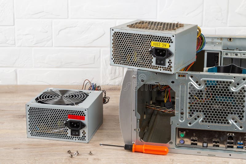 New power supply unit and a screwdriver near tower case with removed old dusty one on a desk. Personal computer PSU replacement. stock photo