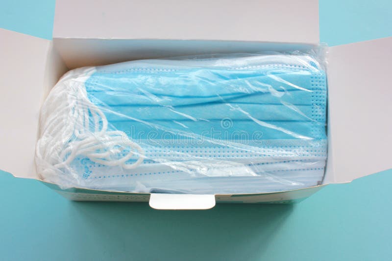 New protective surgical mask in the white card box on the blue background.