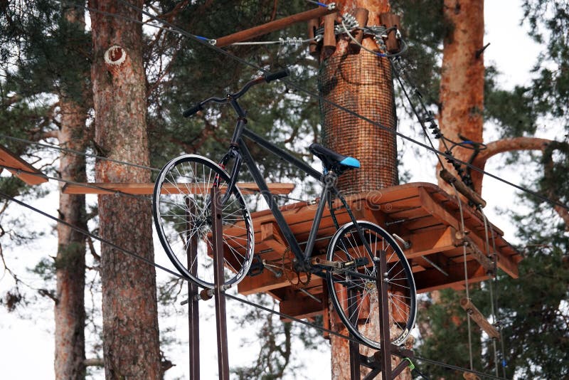 Kiev, Ukraine February 6, 2021: New children`s attractions obstacle course need to ride a bike on a tightrope high between the trees in the park. Kiev, Ukraine February 6, 2021: New children`s attractions obstacle course need to ride a bike on a tightrope high between the trees in the park