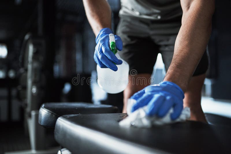 A New Standard of Gym Safety. an Unrecognisable Man Disinfecting the Surfaces in a Gym. Stock