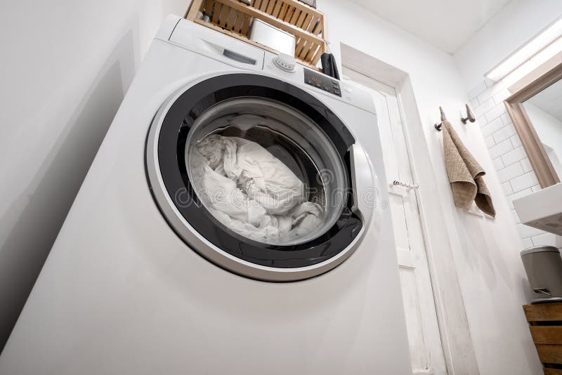 New washing machine with bedding inside, in the interior of a bright bathroom with shelves royalty free stock photography New washing machine with bedding inside, in the interior of a bright bathroom with shelves royalty free stock photography