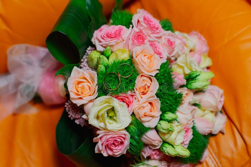 New wedding rings next to the bride`s bouquet.