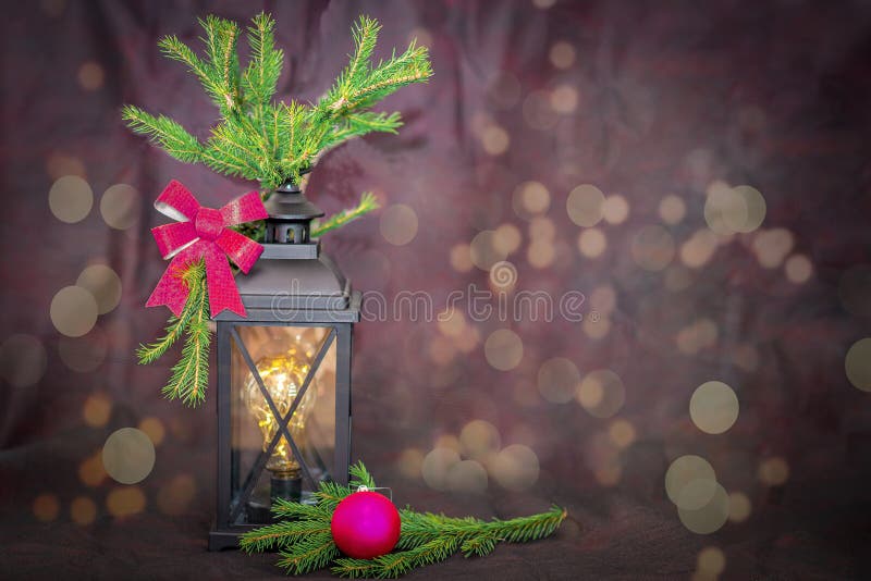 New Year. Ancient lantern, with fir branches and a festive bow, next to a Christmas tree toy purple