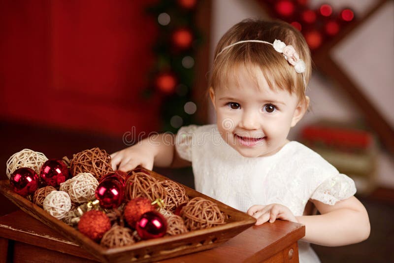 New Year and Christmas celebration concept. Pretty little girl in white dress playing and being happy about christmas tree and stock photos New Year and Christmas celebration concept. Pretty little girl in white dress playing and being happy about christmas tree and stock photos