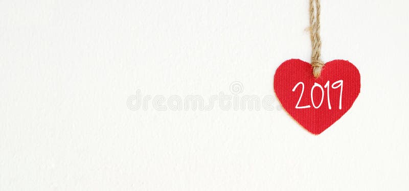 2019 new year greeting card template, Red fabric heart with 2019 word hanging on white wall background with copy space stock photography 2019 new year greeting card template, Red fabric heart with 2019 word hanging on white wall background with copy space stock photography