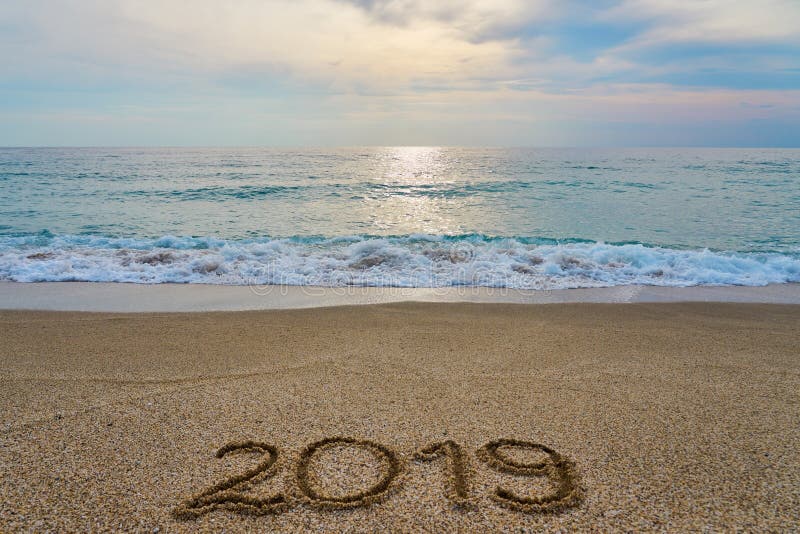 New year 2019 inscription written on the sand with waving sea on a sunset. royalty free stock photo New year 2019 inscription written on the sand with waving sea on a sunset. royalty free stock photo