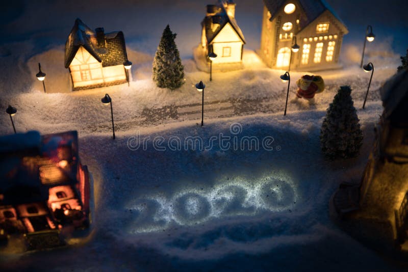 Little decorative cute small houses in snow at night in winter, Christmas and New Year miniature house in the snow at night with fir tree. Holiday concept. Selective focus