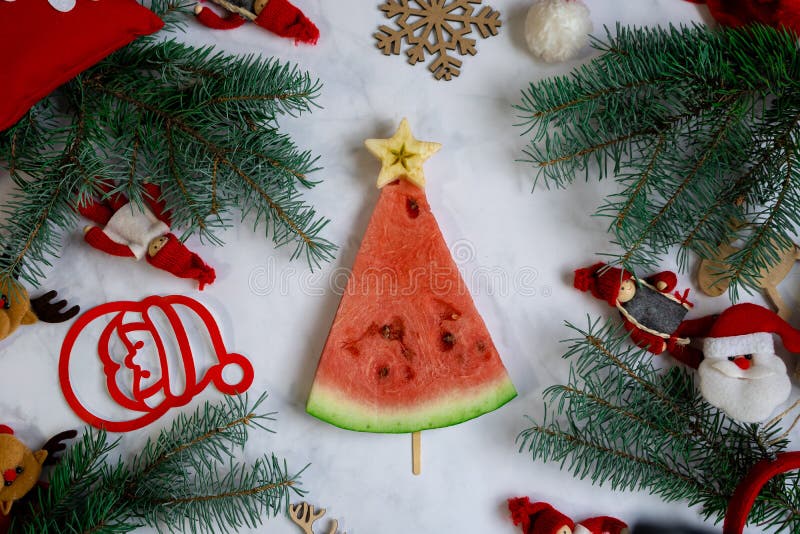 New Year`s food. Christmas tree made of watermelon top view. Christmas decor on the table. Festive still life. Spruce branches an