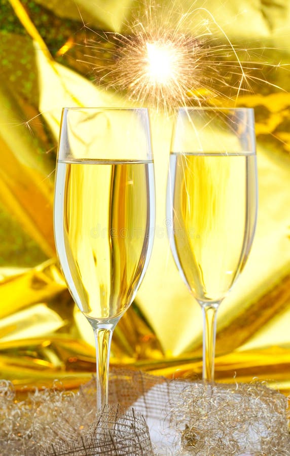 Two filled sparkling wine glasses in front of golden background. Two filled sparkling wine glasses in front of golden background