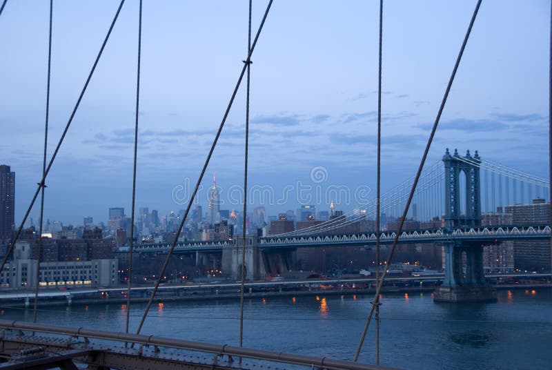 New York City skyline with Empire State Building and Manhattan Bridge as seen from the Brooklyn Bridge near sunset. New York City skyline with Empire State Building and Manhattan Bridge as seen from the Brooklyn Bridge near sunset