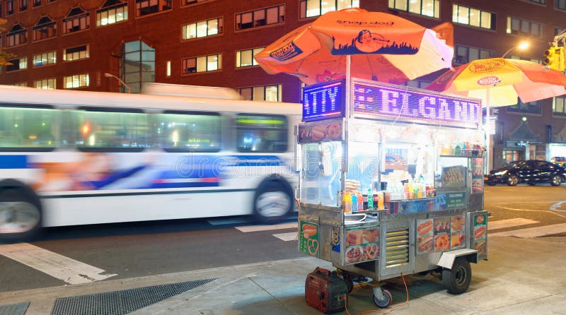 NEW YORK CITY - OCTOBER 23, 2015: Street food vendor at night in Midtown Manhattan. The city attracts 50 million people every year. NEW YORK CITY - OCTOBER 23, 2015: Street food vendor at night in Midtown Manhattan. The city attracts 50 million people every year.