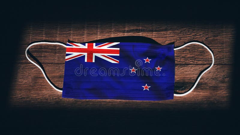 New Zealand National Flag at medical, surgical, protection mask on black wooden background. Coronavirus Covidâ€“19, Prevent infection, illness or flu. State of Emergency, Lockdown