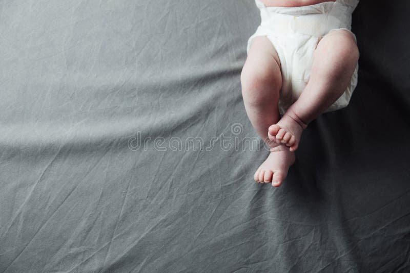 Belly and legs of a newborn baby in a bodysuit lying on a light bed, top  view 13628804 Stock Photo at Vecteezy
