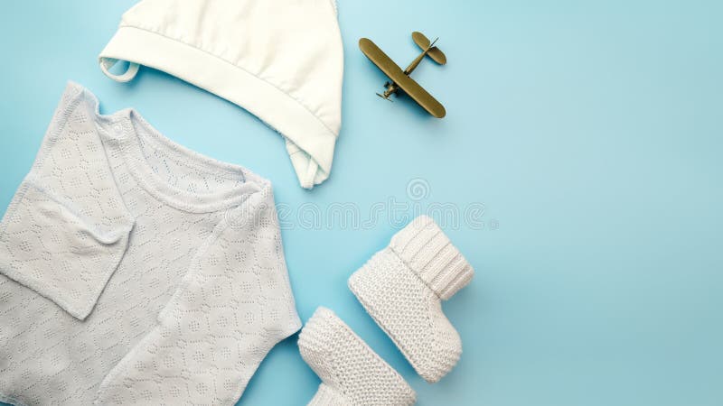 Flatlay of newborn baby boy clothes. Kit of dress for baby on blue background. Copy space. stock photo