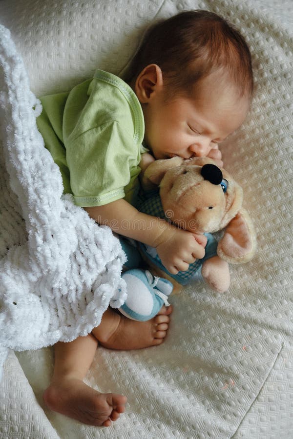 Newborn baby boy sleeping on pillow under the knitted plaid with puppy toy indoor. Cute and pretty. Home care and cozy. Motherhood. royalty free stock photos Newborn baby boy sleeping on pillow under the knitted plaid with puppy toy indoor. Cute and pretty. Home care and cozy. Motherhood. royalty free stock photos