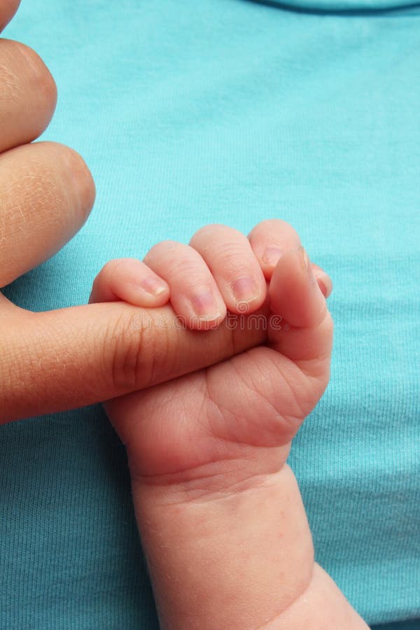 Newborn baby clutching mothers finger