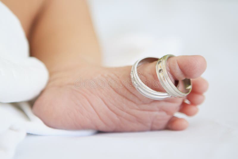 Foot of newborn baby and his parents wedding rings. Foot of newborn baby and his parents wedding rings