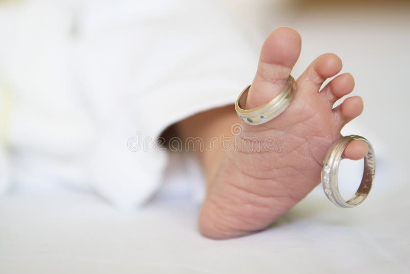 Foot of newborn baby and his parents wedding rings. Foot of newborn baby and his parents wedding rings