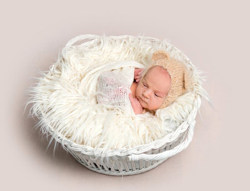 Newborn baby in funny bonnet napping in basket stock photos Newborn baby in funny bonnet napping in basket stock photos