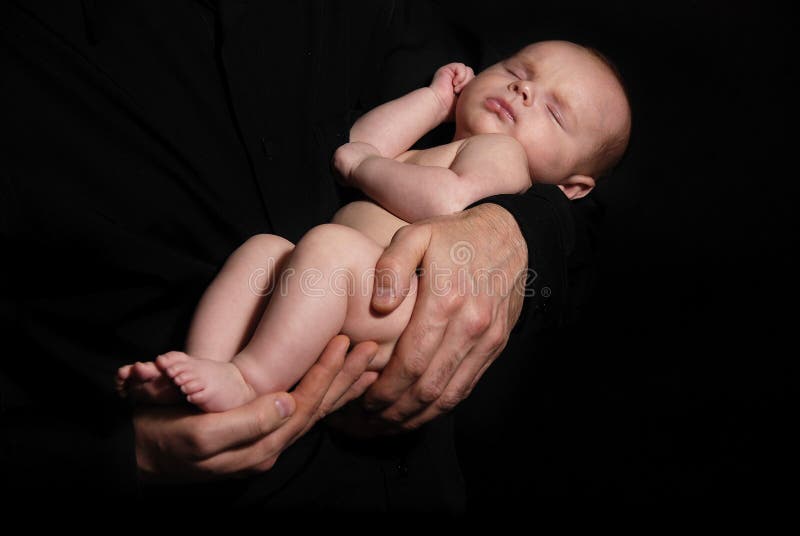 Neonato dorme su mani del padre sullo sfondo nero.