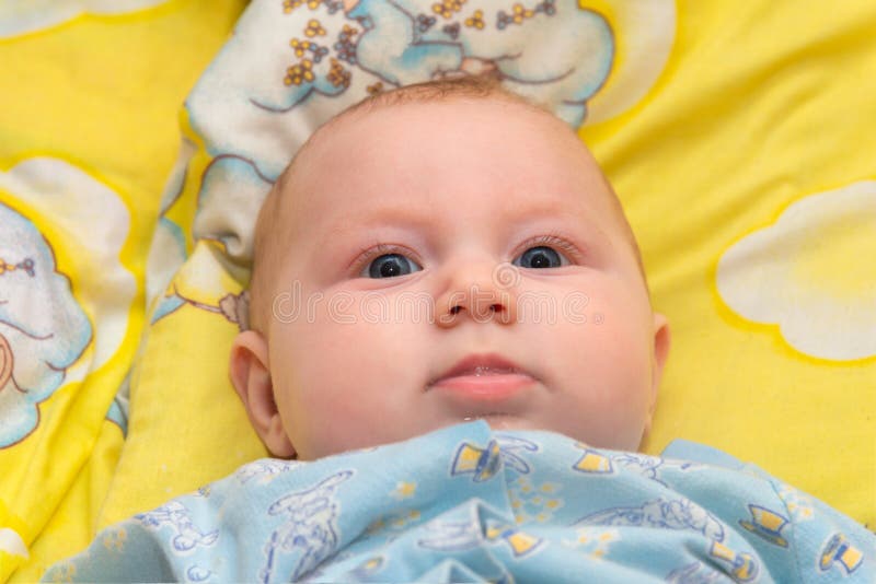 Newborn Baby is Lying in the Baby Bed on a Yellow Background and