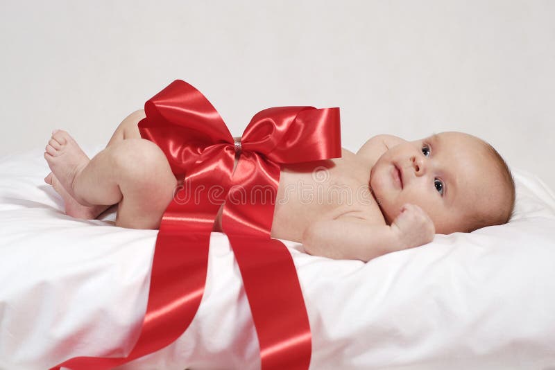 Sdraiato neonato sul cuscino avvolto con grande fiocco rosso.