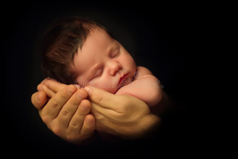 Newborn Baby taken closeup in father`s Hand - black and white