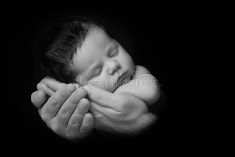 Newborn Baby taken closeup in father`s Hand - black and white