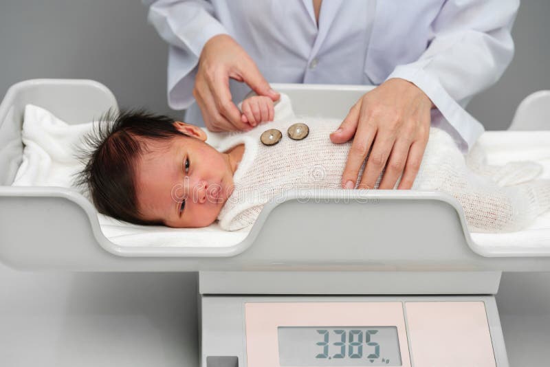 Weighing a newborn / new born baby with weighing scales / scale soon after  childbirth / giving birth in an NHS hospital Stock Photo - Alamy