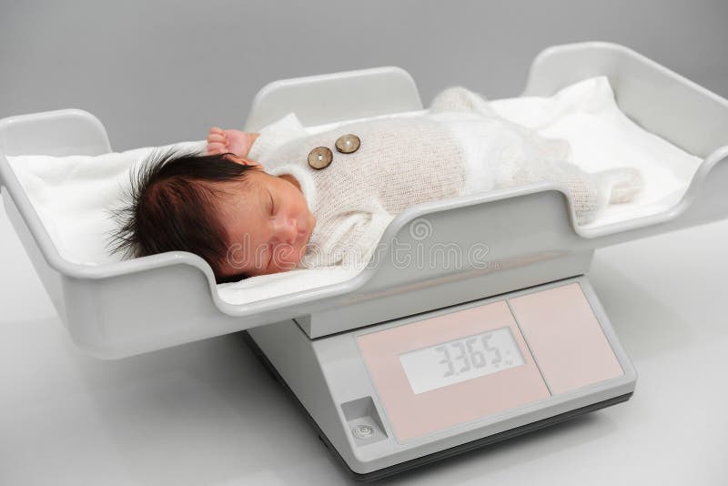 Weighing a newborn / new born baby with weighing scales / scale soon after  childbirth / giving birth in an NHS hospital Stock Photo - Alamy