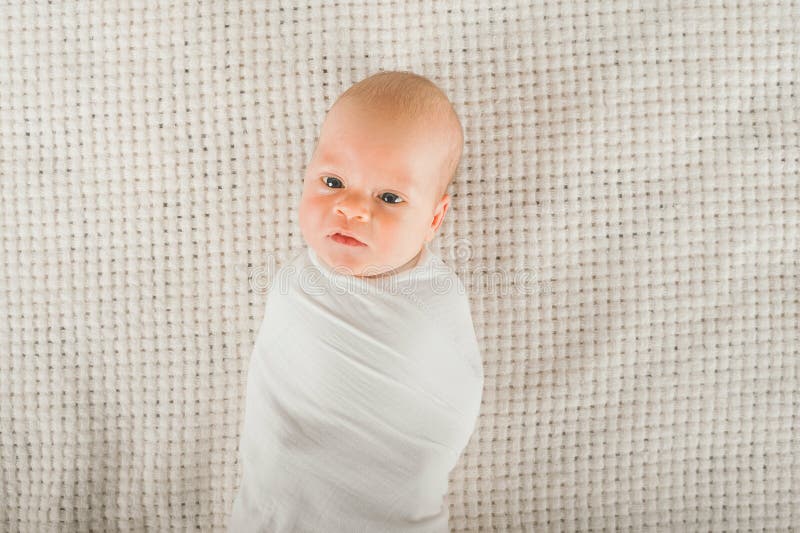 Newborn Baby in a White Diaper Close Up. Baby Swaddling in Muslin Diaper and Copy Space Stock