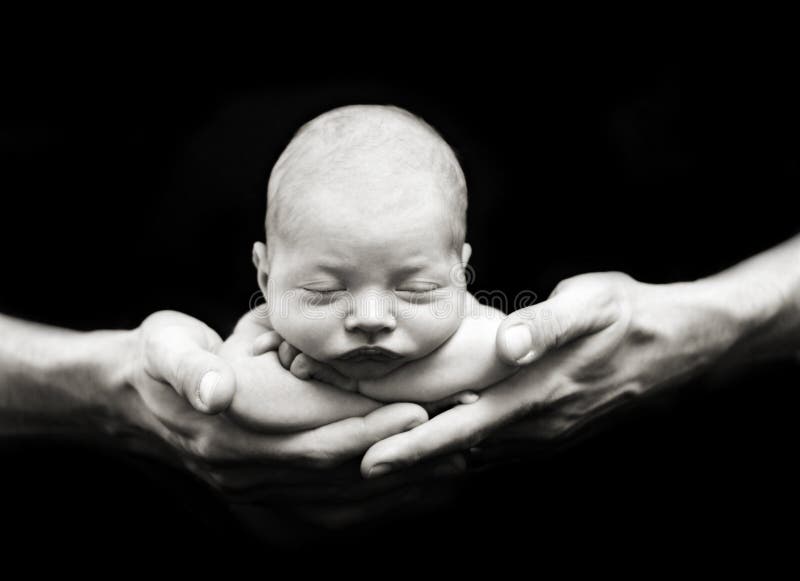 Neonato in mano, profondità di campo, chiave bassa illuminazione.