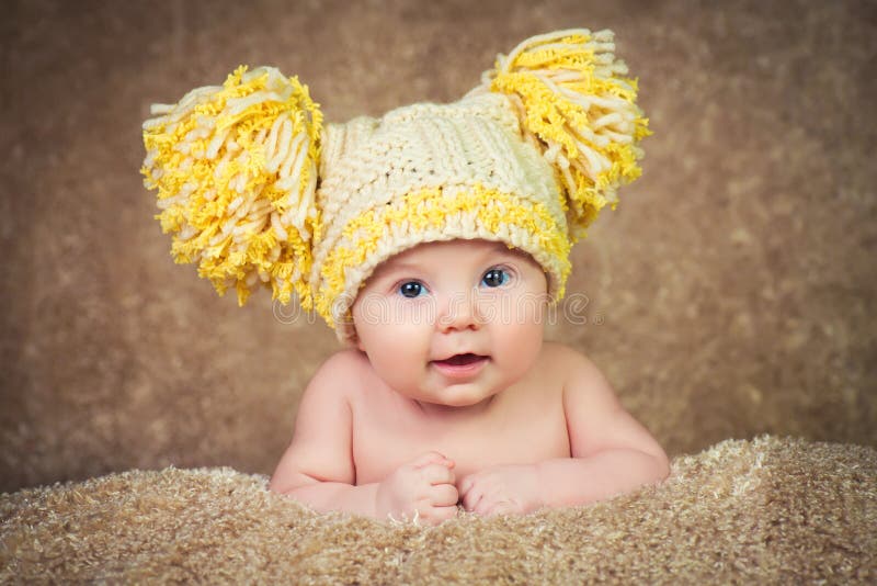 Newborn in knitted winter hat on a beige background. stock photo Newborn in knitted winter hat on a beige background. stock photo