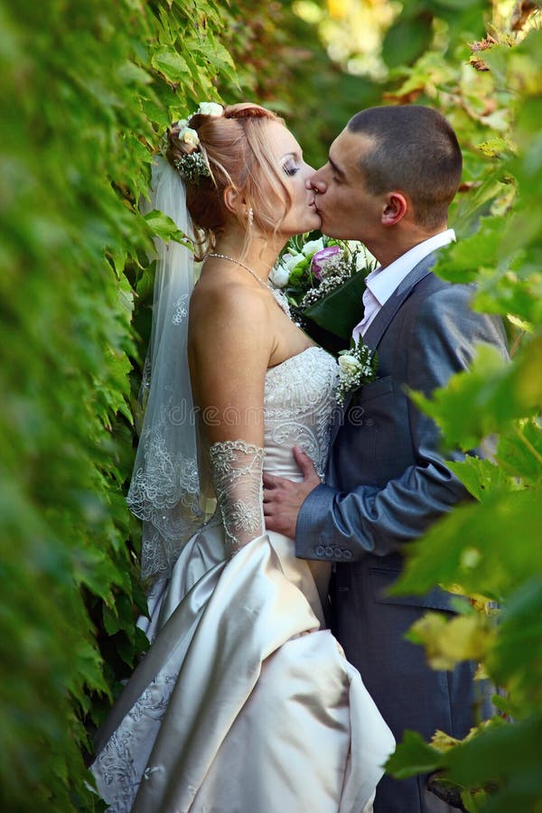 Newly-married couple kisses in a vineyard