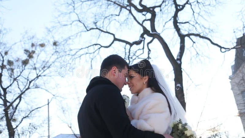 Newly-married couple kisses in winter