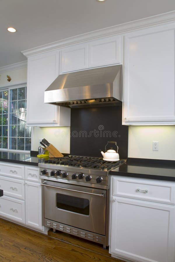 Colpo interno di una cucina recentemente ristrutturata con il bianco personalizzato armadi, elettrodomestici in acciaio inox e un pavimento in rovere.