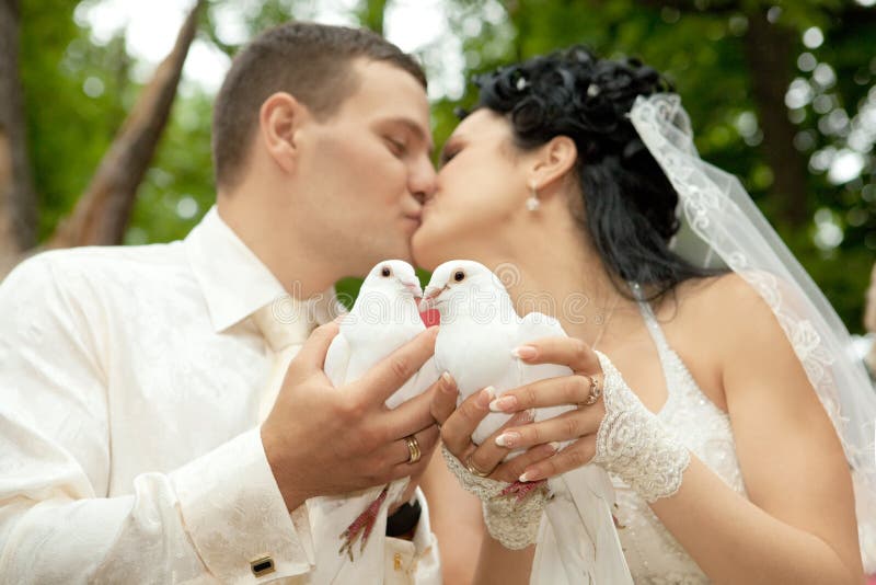 Newlyweds kissing holding white doves