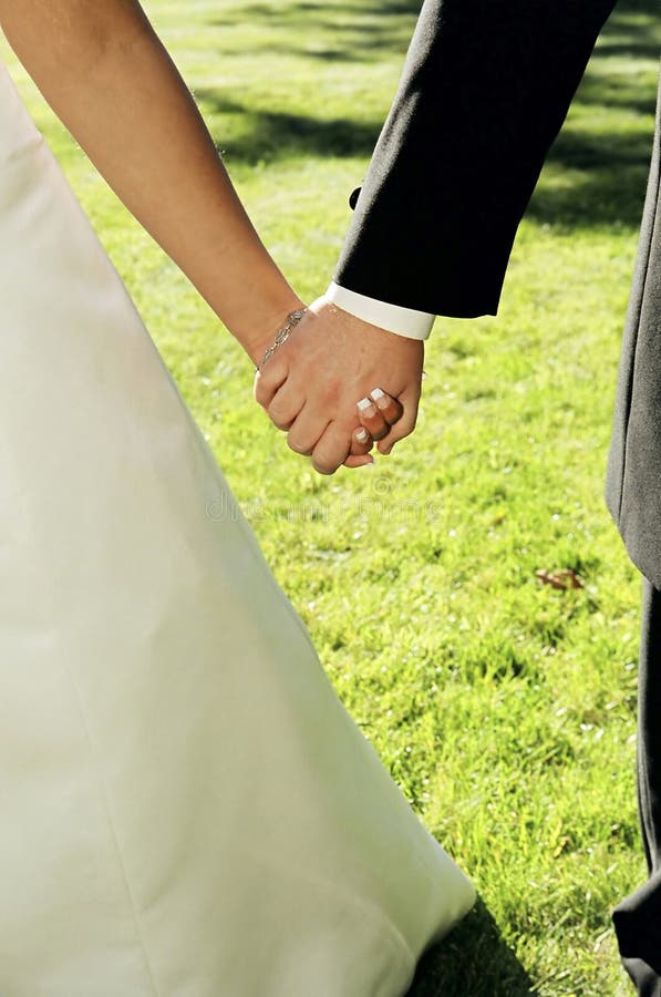 Bride and groom holding hands on wedding day. Bride and groom holding hands on wedding day