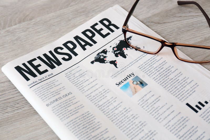 Newspaper with glasses on wooden background royalty free stock photo