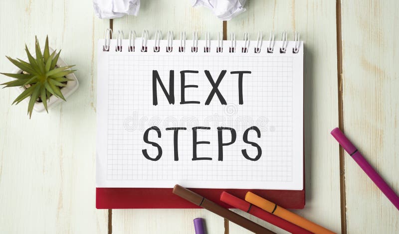 NEXT STEPS text on wooden desk with tablet pc