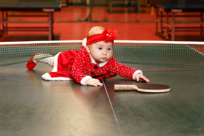 Niña Seis Meses De Edad Vestida Con Un Traje De Papá Rojo En Navidad En La Mesa De Tenis Con Un Imagen de archivo - Imagen de bebés, imagen:
