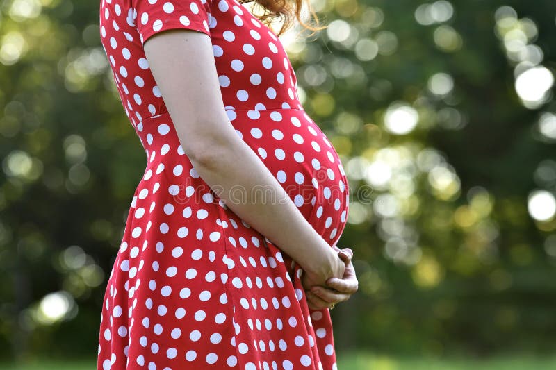 Niña En El Mes De Embarazo Un Vestido Rojo Con Puntos De Polka Blanco. Fondo Verde Arbolado Y Exterior. Foto de archivo - Imagen puntos, hembra: 191402258