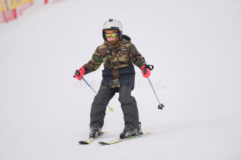 Niño Pequeño Con Casco Y Palo De Traje De Esquí De Color Verde Militar Durante El Esquí En Pista De Invierno De Nieve En La Est Imagen de archivo - Imagen