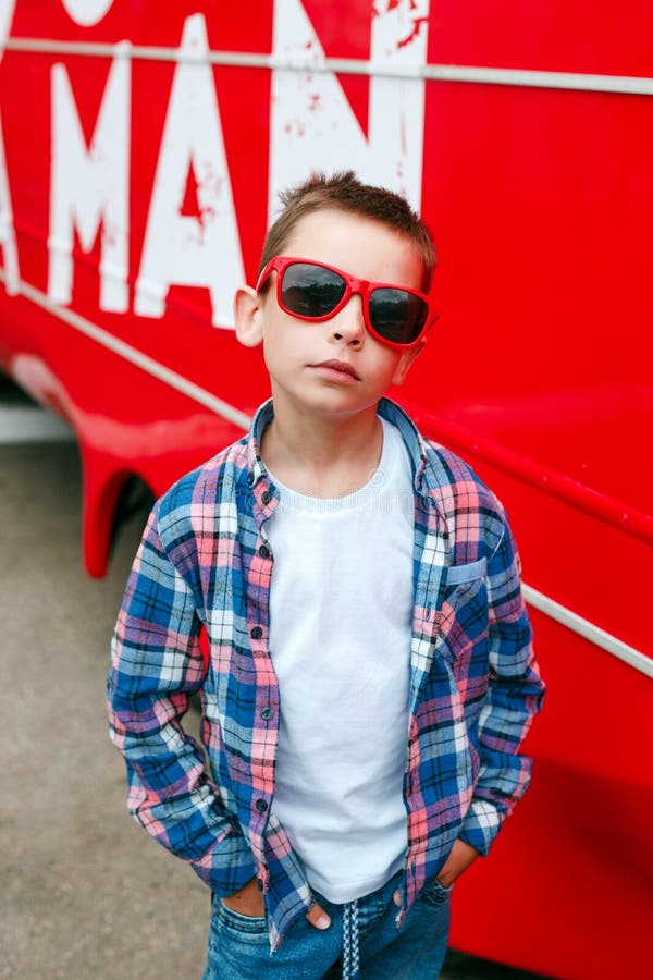 Niño Pequeño Del Retrato Que Lleva Una Camisa a Cuadros Y Las Gafas De Sol  En Ciudad Sobre Fondo Rojo Foto de archivo - Imagen de encantador,  fashionable: 153196644