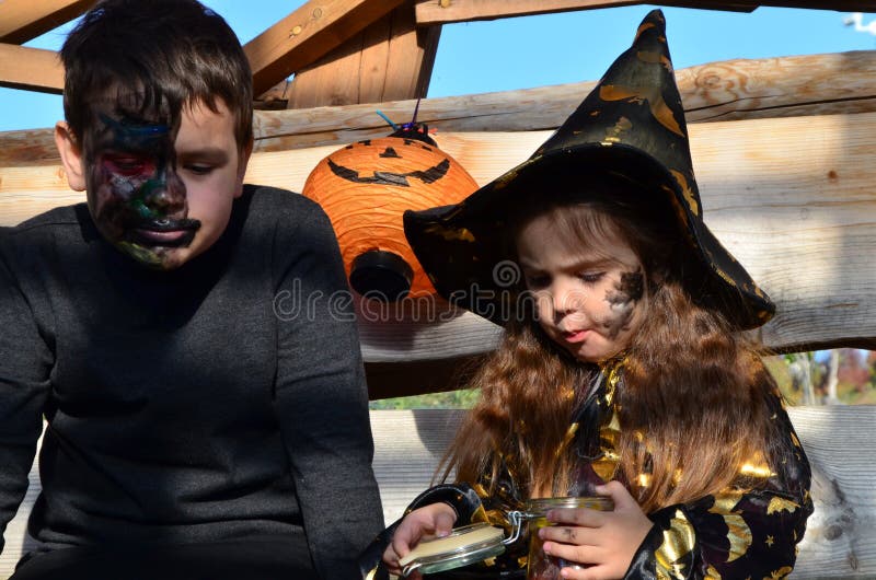 Niños En Disfraces De Halloween En Vacaciones Una Chica En Traje De Bruja Un Sombrero Negro En La Cabeza Con Maquillaje Negro De H Imagen de archivo - Imagen de anaranjado, halloween: Niños En Disfraces De Halloween En Vacaciones Una Chica En Traje De Bruja Un Sombrero Negro En La Cabeza Con Maquillaje Negro De H Imagen de archivo - Imagen de anaranjado, halloween: