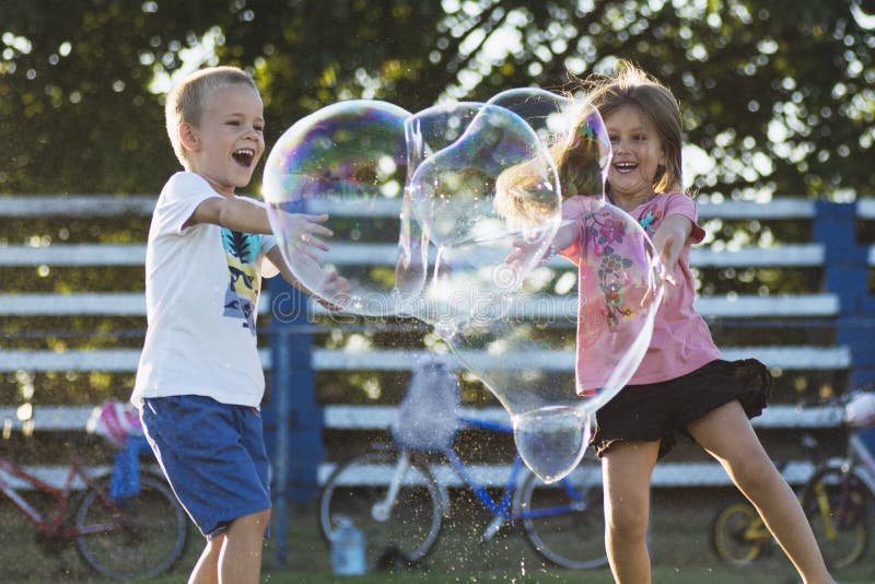 Niños jugando con pompas de jabón en el parque.