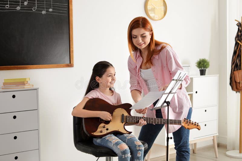 Ni?a que toca la guitarra con su profesor en la lecci?n de m?sica imagen de archivo Ni?a que toca la guitarra con su profesor en la lecci?n de m?sica imagen de archivo