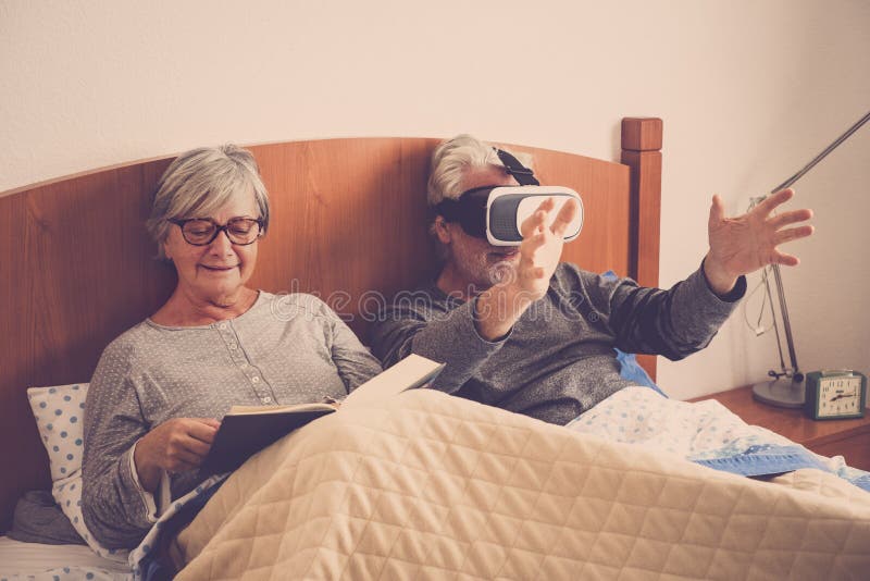 Nice beautiful couple caucasian matures man and woman at home in the bedroom stay on the bed during a morning. she read a paper stock image Nice beautiful couple caucasian matures man and woman at home in the bedroom stay on the bed during a morning. she read a paper stock image