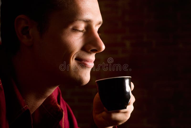 Hombre bebiendo café sobre el ladrillo.